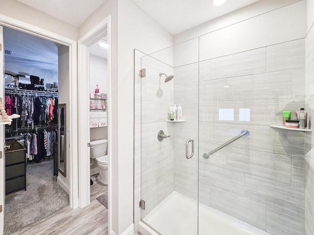 68 Los Lagos Blvd, Palm Coast, FL 32137 - bathroom with a shower stall, toilet, wood finished floors, a walk in closet, and baseboards
