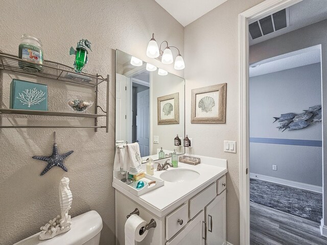 68 Los Lagos Blvd, Palm Coast, FL 32137 - bathroom with wood finished floors, vanity, toilet, and a textured wall