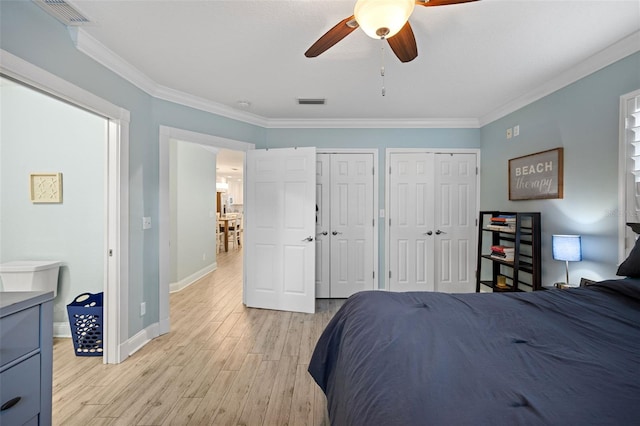 bedroom with two closets, crown molding, baseboards, light wood-style floors, and visible vents