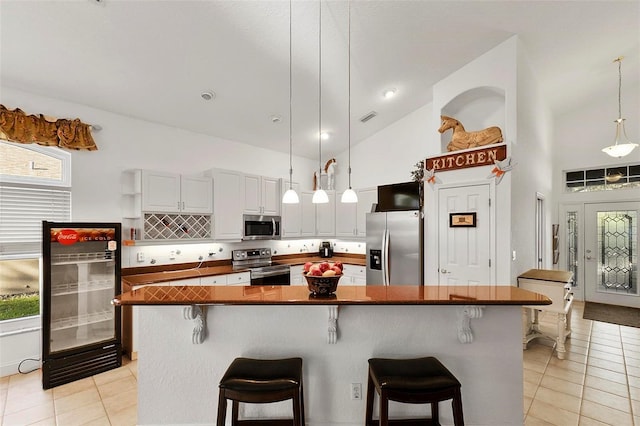 3220 Galty Cir, Ormond Beach, FL 32174 - kitchen featuring appliances with stainless steel finishes, light tile patterned flooring, high vaulted ceiling, a breakfast bar, and pendant lighting