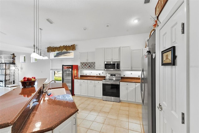 3220 Galty Cir, Ormond Beach, FL 32174 - kitchen featuring stainless steel appliances, a sink, dark countertops, white cabinetry, and light tile patterned floors