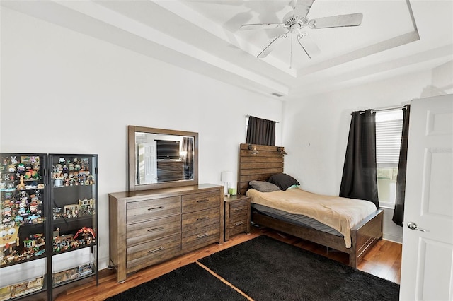 3220 Galty Cir, Ormond Beach, FL 32174 - bedroom with light wood-style flooring, a tray ceiling, and a ceiling fan