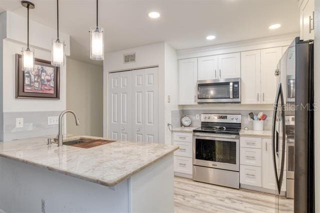 31 Catalonia Court E, Saint Augustine, FL 32086 - kitchen featuring visible vents, a sink, white cabinetry, stainless steel appliances, and light stone counters