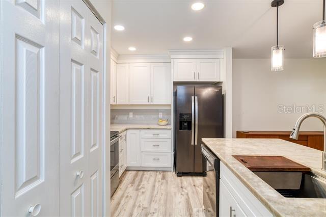 31 Catalonia Court E, Saint Augustine, FL 32086 - kitchen featuring hanging light fixtures, a sink, appliances with stainless steel finishes, light wood-style floors, and white cabinetry