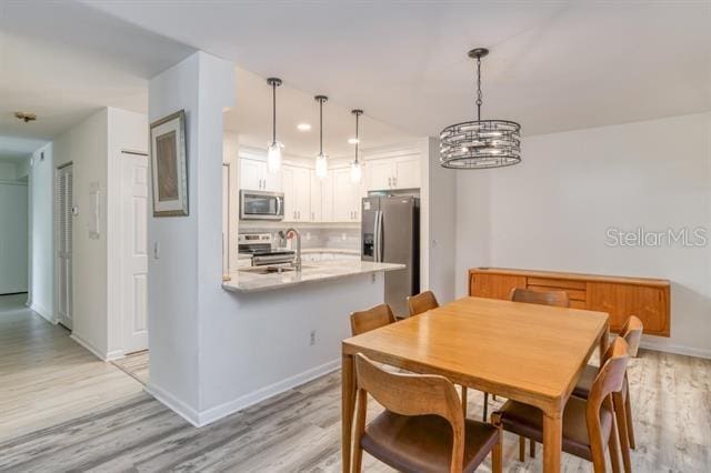 31 Catalonia Court E, Saint Augustine, FL 32086 - dining room featuring light wood finished floors, baseboards, and an inviting chandelier