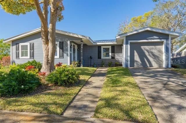 single story home with aphalt driveway, a garage, a front yard, and metal roof