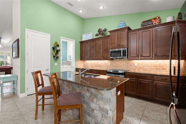 1316 Harwick Ln, Ormond Beach, FL 32174 - kitchen featuring stainless steel appliances, a sink, light tile patterned floors, dark stone counters, and high vaulted ceiling
