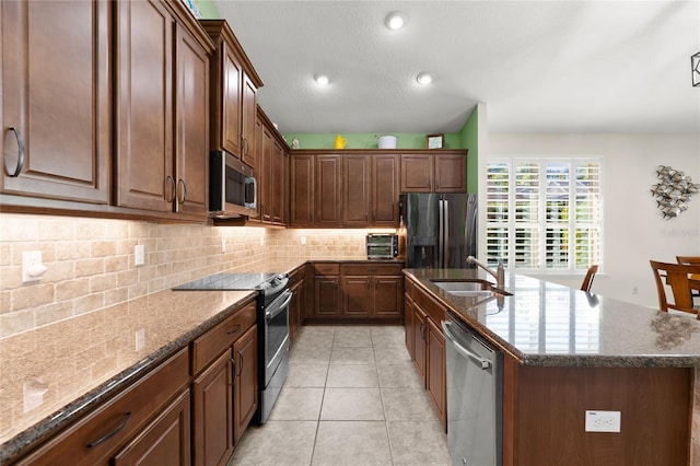 1316 Harwick Ln, Ormond Beach, FL 32174 - kitchen featuring appliances with stainless steel finishes, a sink, decorative backsplash, a kitchen island with sink, and dark stone countertops