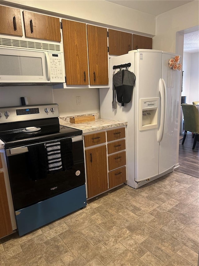 787 Alhambra Ave, Saint Augustine, FL 32086 - kitchen with light countertops, stone finish flooring, brown cabinetry, and white appliances
