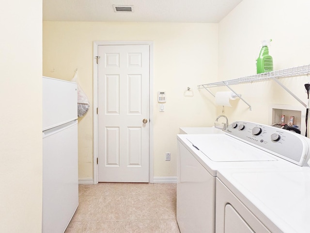 laundry area featuring laundry area, light tile patterned floors, a sink, visible vents, and washing machine and dryer