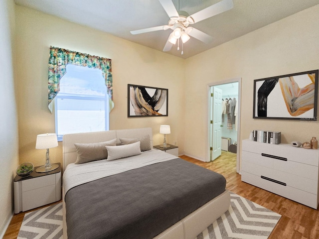 bedroom with radiator, a ceiling fan, light wood-style flooring, and ensuite bath