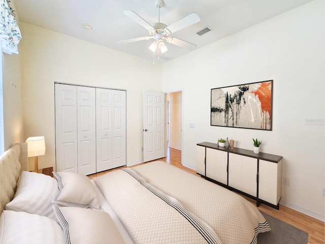bedroom with a closet, ceiling fan, light wood finished floors, baseboards, and visible vents