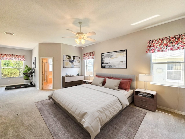 bedroom featuring ensuite bathroom, visible vents, light colored carpet, and baseboards