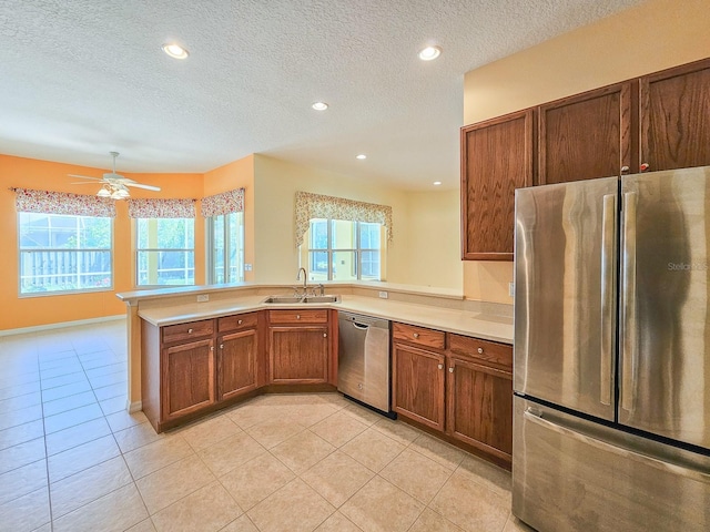 kitchen featuring appliances with stainless steel finishes, brown cabinets, plenty of natural light, and a sink