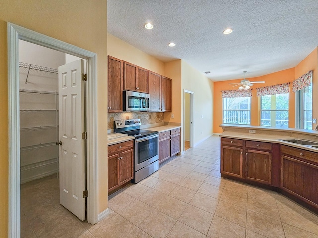 kitchen featuring brown cabinets, decorative backsplash, light tile patterned floors, light countertops, and appliances with stainless steel finishes
