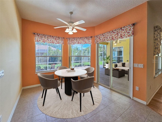 dining room featuring a textured ceiling, ceiling fan, light tile patterned floors, and baseboards