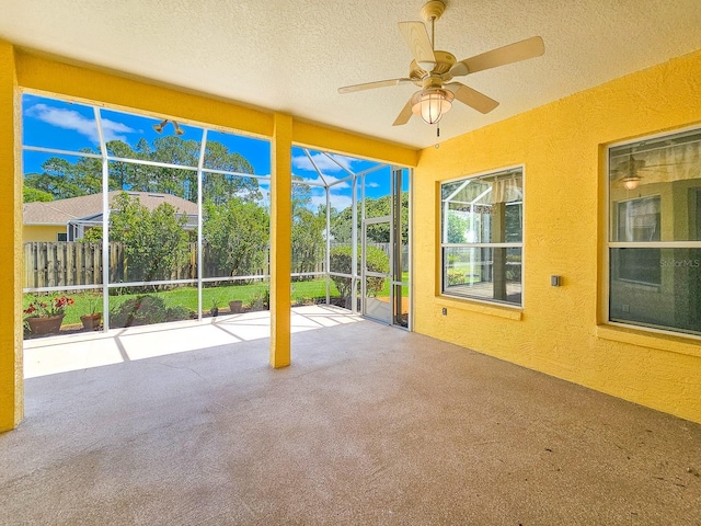 unfurnished sunroom with a textured ceiling, carpet, and a textured wall