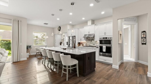 29 Old Oak Dr S, Palm Coast, FL 32137 - kitchen featuring an island with sink, backsplash, under cabinet range hood, stainless steel appliances, and visible vents