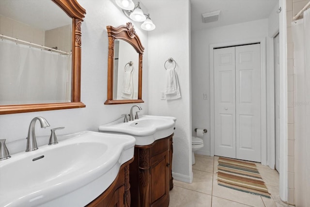 bathroom with tile patterned floors, a closet, toilet, and a sink