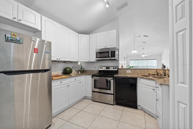 kitchen with white cabinets, appliances with stainless steel finishes, a sink, vaulted ceiling, and light tile patterned floors