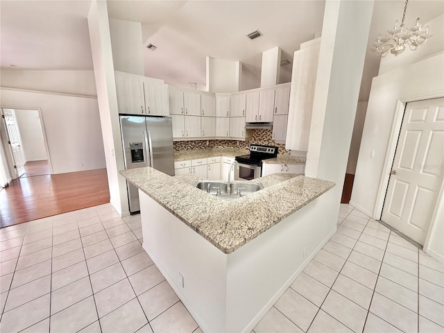 kitchen with light tile patterned flooring, a peninsula, appliances with stainless steel finishes, a sink, and backsplash