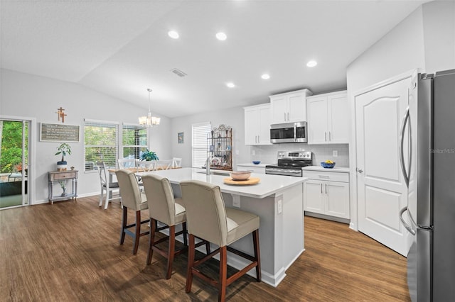 324 Palace Dr, Saint Augustine, FL 32084 - kitchen featuring appliances with stainless steel finishes, dark wood-style flooring, a kitchen island with sink, plenty of natural light, and vaulted ceiling