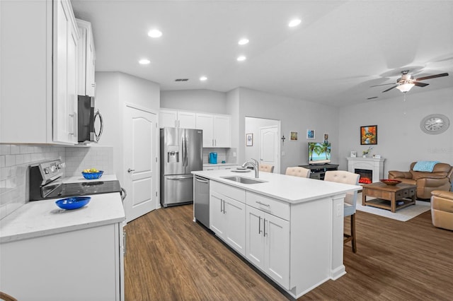 324 Palace Dr, Saint Augustine, FL 32084 - kitchen with stainless steel appliances, open floor plan, a ceiling fan, a warm lit fireplace, and white cabinetry