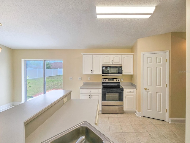 18 Wheatfield Dr, Palm Coast, FL 32164 - kitchen with appliances with stainless steel finishes, a textured ceiling, white cabinetry, light countertops, and light tile patterned flooring