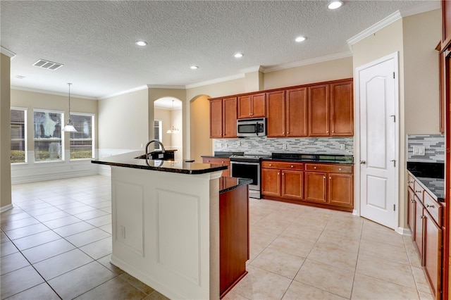 4484 Gray Hawk St, Orange Park, FL 32065 - kitchen with light tile patterned floors, stainless steel appliances, arched walkways, an island with sink, and visible vents
