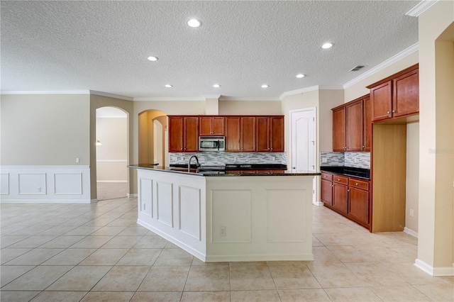 4484 Gray Hawk St, Orange Park, FL 32065 - kitchen featuring stainless steel microwave, light tile patterned flooring, dark countertops, and arched walkways