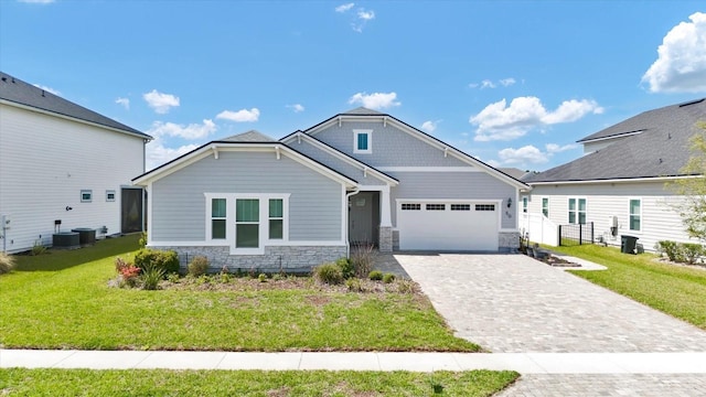 view of front of property featuring decorative driveway, an attached garage, stone siding, and a front lawn