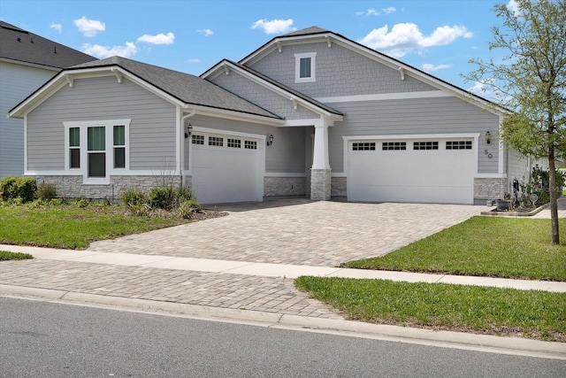 craftsman house with driveway, stone siding, and an attached garage
