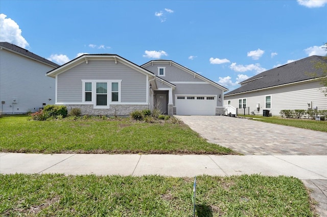 view of front of house featuring a garage, a front yard, stone siding, and decorative driveway
