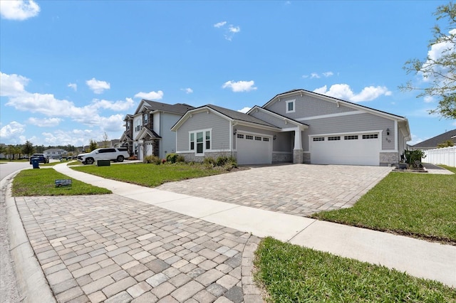 single story home with a front yard, stone siding, a garage, fence, and decorative driveway