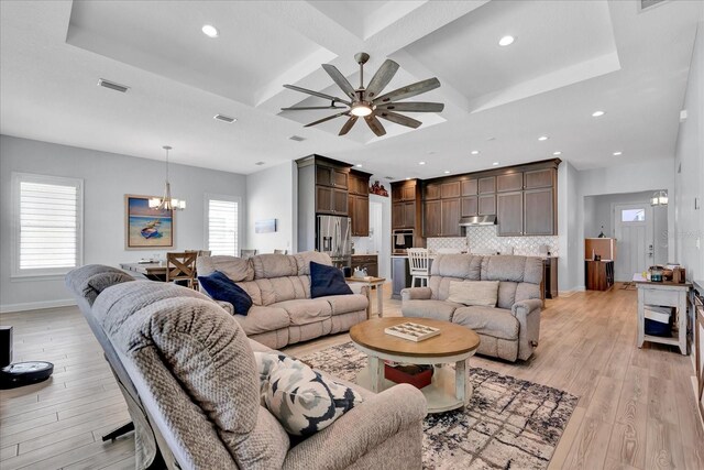 living area with coffered ceiling, ceiling fan with notable chandelier, light wood finished floors, and baseboards