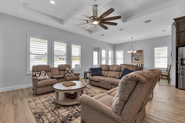 living area featuring baseboards, plenty of natural light, visible vents, light wood finished floors, and ceiling fan with notable chandelier