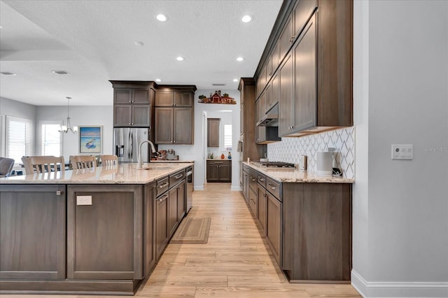 kitchen featuring a healthy amount of sunlight, under cabinet range hood, light wood-style flooring, and appliances with stainless steel finishes