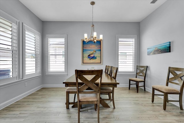 dining room featuring light wood-style flooring, a healthy amount of sunlight, and an inviting chandelier