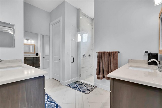 full bath featuring ceiling fan, two vanities, a marble finish shower, and a sink