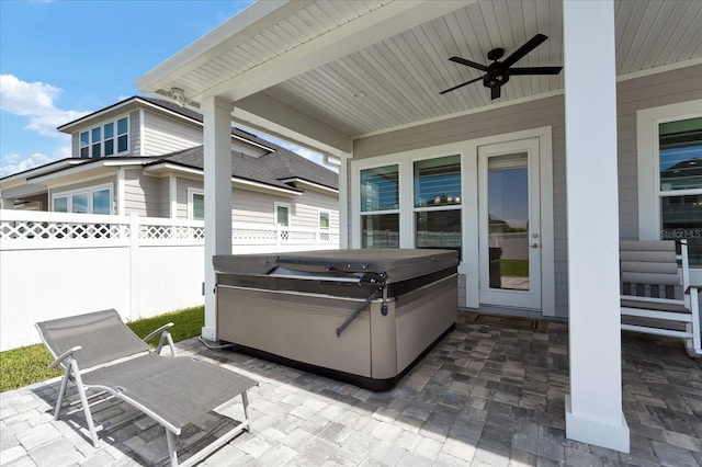 view of patio / terrace featuring ceiling fan, fence, and a hot tub