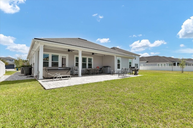 back of house featuring a hot tub, a yard, a ceiling fan, a patio area, and fence