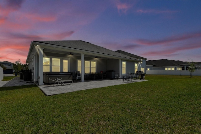 rear view of house with a hot tub, a ceiling fan, a lawn, a patio area, and fence