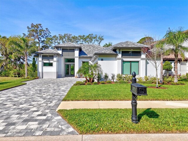 21 N Riverwalk Dr, Palm Coast, FL 32137 - prairie-style house with stucco siding, french doors, a front yard, and decorative driveway