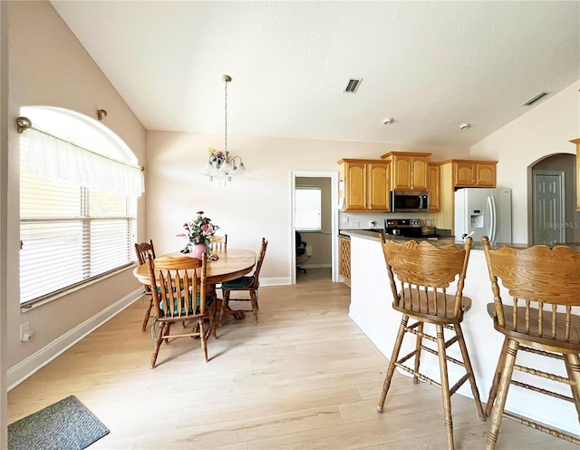 161 Frontier Dr, Palm Coast, FL 32137 - kitchen with white fridge with ice dispenser, stainless steel microwave, lofted ceiling, light wood-style floors, and healthy amount of natural light