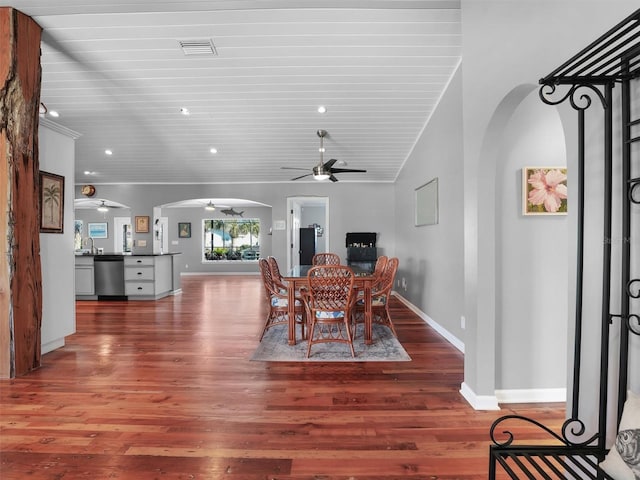 dining area featuring a ceiling fan, visible vents, arched walkways, wood finished floors, and wooden ceiling