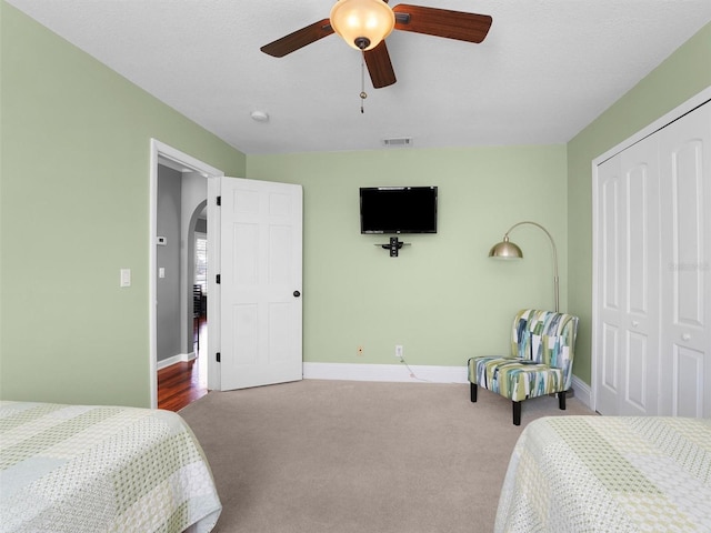 bedroom with a closet, arched walkways, baseboards, and carpet flooring