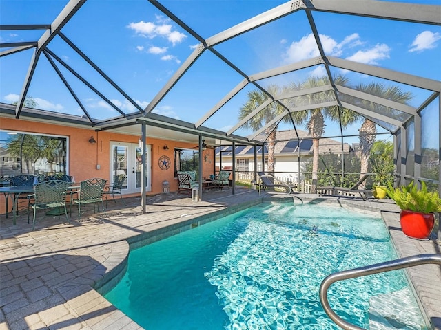outdoor pool with a patio, glass enclosure, and french doors