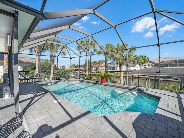 pool with glass enclosure, a water view, and a patio area