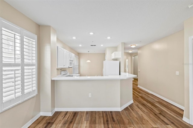 500 Canopy Walk Ln Unit 515, Palm Coast, FL 32137 - kitchen with white appliances, wood finished floors, white cabinets, recessed lighting, and a peninsula