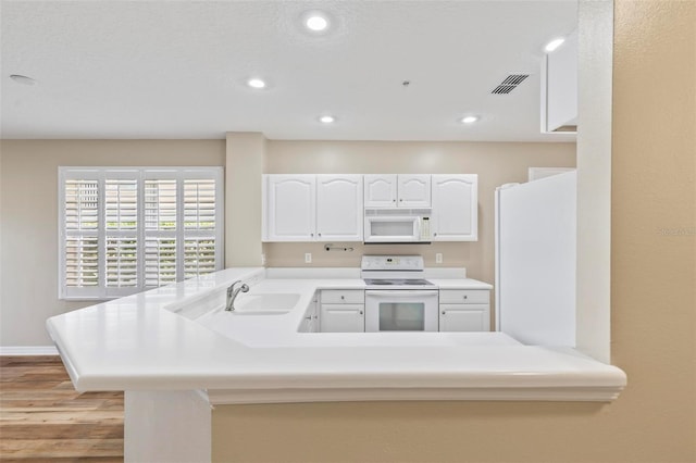 500 Canopy Walk Ln Unit 515, Palm Coast, FL 32137 - kitchen with white appliances, a peninsula, light wood-type flooring, white cabinets, and recessed lighting